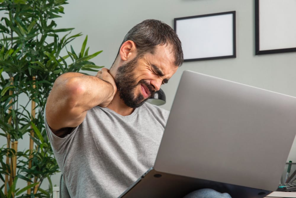 Homme faisant du télétravail a mal au cou