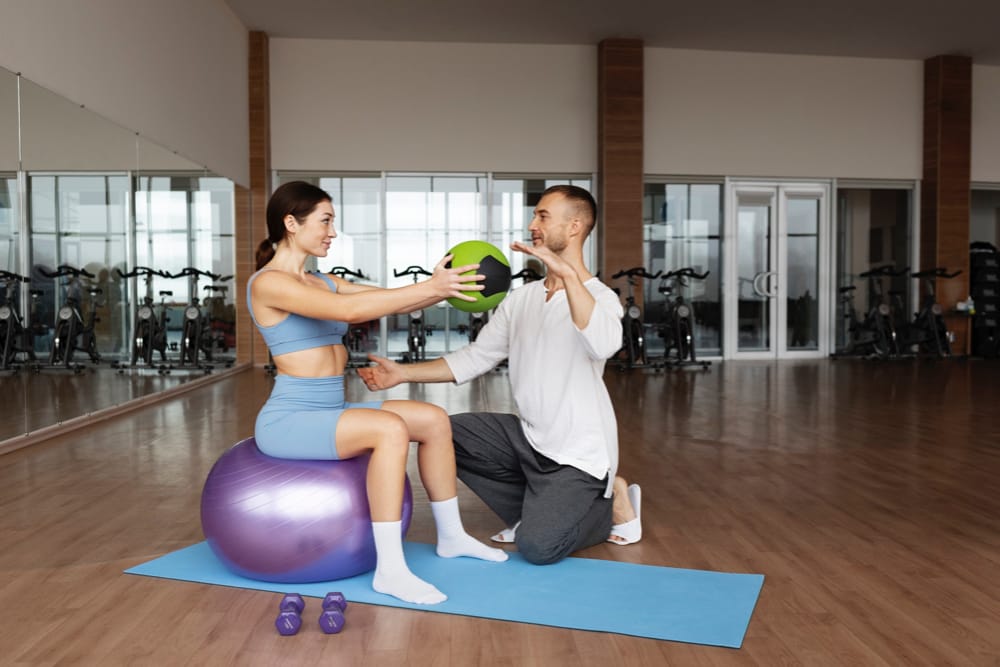femme assise sur un ballon d'exercice en séance de physiothérapie