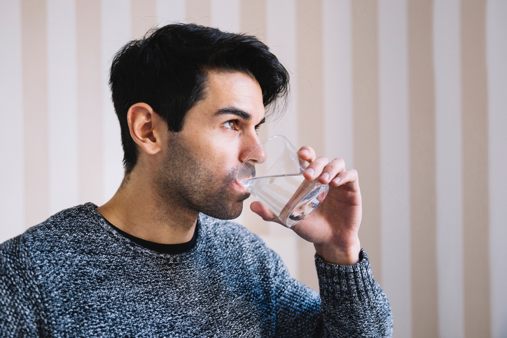 Photo d'un homme quit boit un verre d'eau.